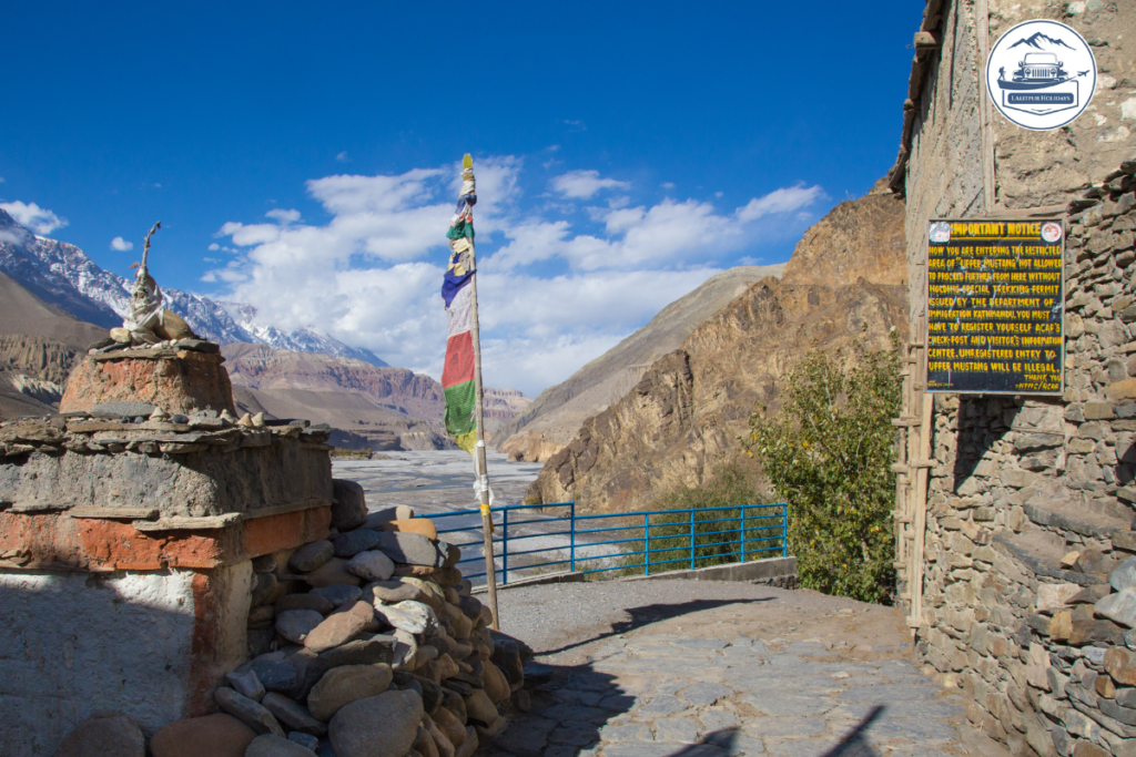 Upper Mustang restricted-area entrance with prayer flags and Kali Gandaki valley