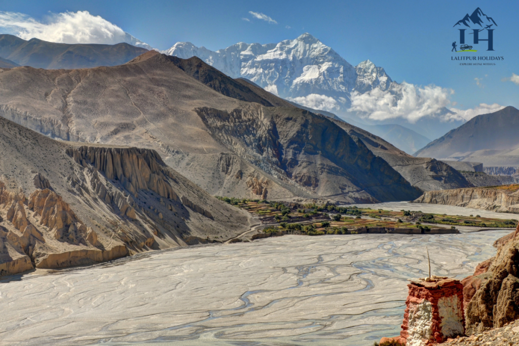 upper mustang valley with dry cliffs, riverbed, fields and snow covered mountains